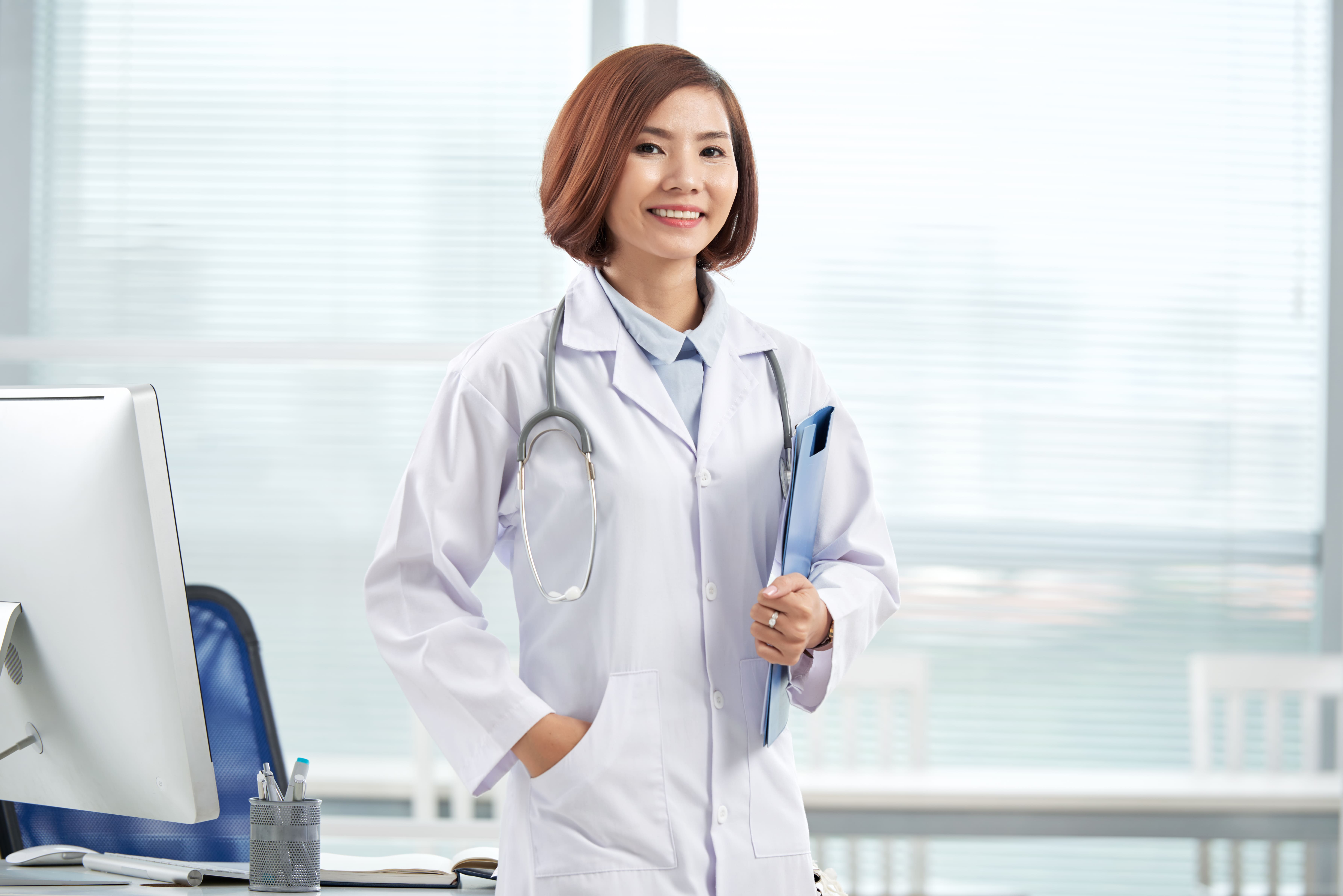 smiling-pretty-doctor-standing-hospital-office-with-paper-folder