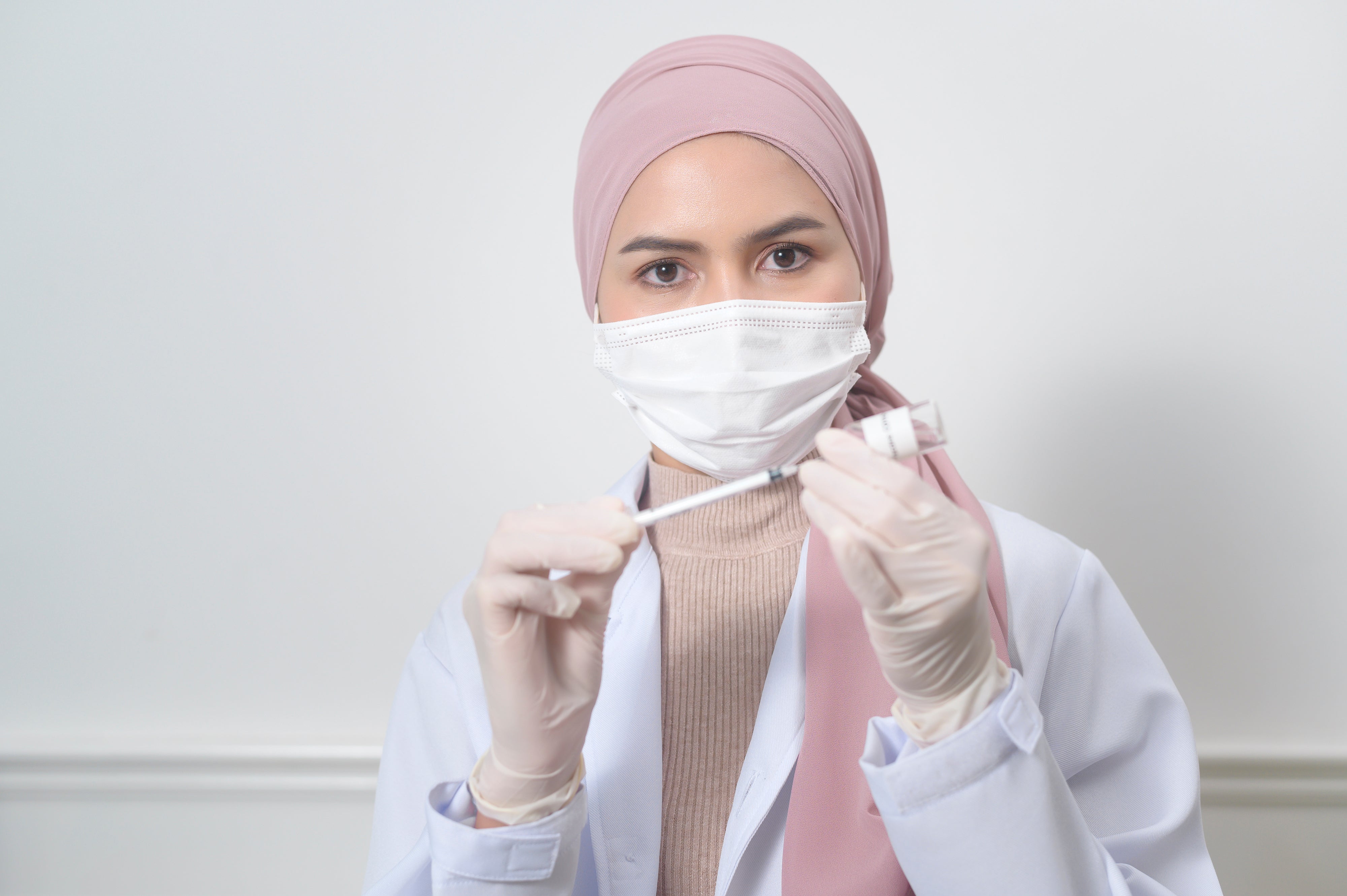 Young female muslim doctor holding srynge
